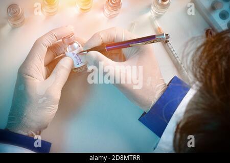 Le personnel du laboratoire écrit sur des flacons contenant le vaccin Covid-19. Composition horizontale. Vue de dessus. Banque D'Images