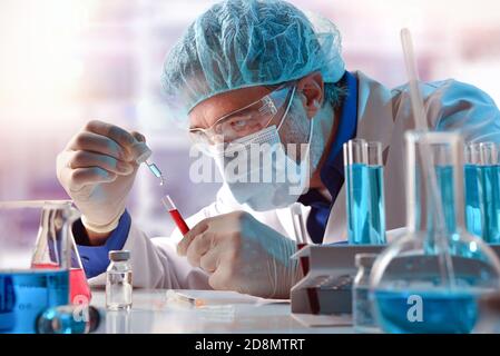 Chercheur en laboratoire versant un réactif à l'aide d'une pipette dans un échantillon dans un tube à essai avec échantillon. Composition horizontale. Vue avant. Banque D'Images