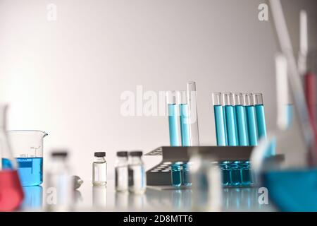 Concept de recherche de flacons de vaccins sur table autour de la verrerie chimique sur banc blanc. Vue avant. Composition horizontale. Banque D'Images