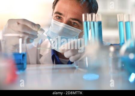 Détail de l'analyse du liquide bleu à partir d'une pipette par un technicien de laboratoire. Composition horizontale. Vue avant. Banque D'Images