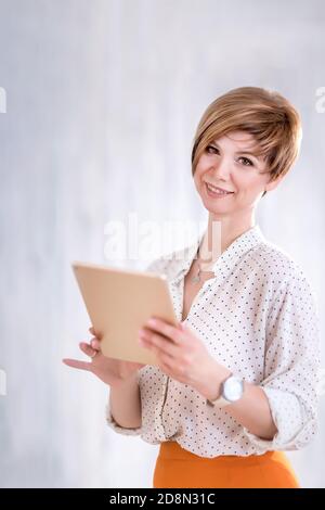 Portrait d'une femme heureuse debout avec un bloc-notes et un stylo. Une femme d'affaires réfléchit et rédige son plan de travail. Propriétaire réussi de petite entreprise je Banque D'Images