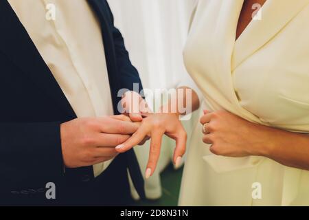 Des anneaux d'échange de jeunes mariés, marié met l'anneau sur la main de la mariée dans le bureau du registre du mariage. Banque D'Images