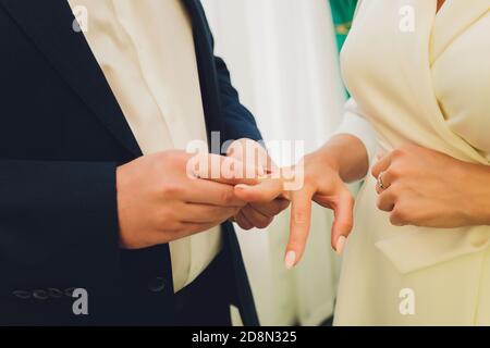 Des anneaux d'échange de jeunes mariés, marié met l'anneau sur la main de la mariée dans le bureau du registre du mariage. Banque D'Images