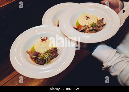 Le serveur est maintenant un plat délicieux rôti de viande juteuse, purée de pommes de terre saupoudrées de verts et frais sain salade de laitue et tomates Banque D'Images