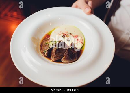 Le serveur est maintenant un plat délicieux rôti de viande juteuse, purée de pommes de terre saupoudrées de verts et frais sain salade de laitue et tomates Banque D'Images