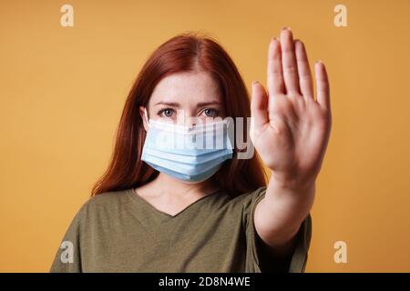 jeune femme portant un masque médical faisant un geste d'arrêt avec sa main - pas d'entrée sans masque pendant corona covid-19 concept de pandémie Banque D'Images