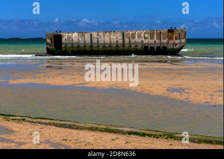 A marée basse à Arromanches, Calvados, Normandie, France, Les gens peuvent marcher jusqu'au bord de l'eau sur la « Gold Beach » de la Seconde Guerre mondiale pour atteindre - mais pas entrer - des sections en béton précoulées de Port Winston ou de Mulberry Harbour B. c'était le port portable préfabriqué de 600,000 tonnes remorqué sur la Manche, Assemblé au large, puis utilisé pendant 10 mois après l’invasion du jour J de l’opération Overlord, le 6 juin 1944, pour atterrir 2.5 millions de troupes britanniques et canadiennes, un demi-million de véhicules et quatre millions de tonnes de fournitures. Banque D'Images