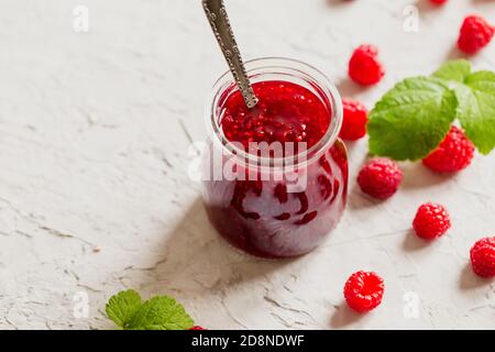 confiture de framboises maison sur fond de béton avec framboises fraîches, mise au point sélective. Banque D'Images