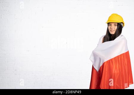 Une adolescente portant un casque de protection a jeté sur ses épaules et en arrière le symbole national de la Pologne, qui est le drapeau du pays. Banque D'Images