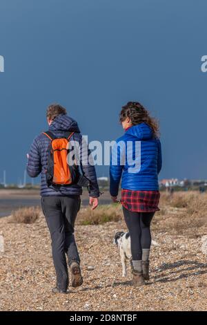 Homme et femme couple marchant sur la plage ensemble à marée basse à la réserve naturelle d'oiseaux de la RSPB à snettisham sur la côte nord de Norfolk en automne Banque D'Images