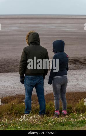 Homme et femme couple marchant sur la plage ensemble à marée basse à la réserve naturelle d'oiseaux de la RSPB à snettisham sur la côte nord de Norfolk en automne Banque D'Images