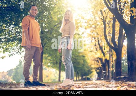 Photo en plein air de jeunes couples amoureux du masque facial, marchant sur le chemin à travers le parc à l'heure du coronavirus - concept sur l'homme et la femme marchant à covi Banque D'Images