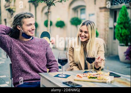 Couple qui boit du vin rouge au bar avec des masques ouverts En temps de coronavirus - Nouveau concept normal - Focus on femmes Banque D'Images