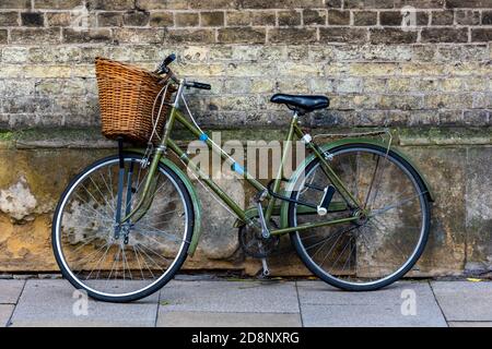 vélo pour femmes vintage à l'ancienne avec un panier à l'avant pour faire du shopping appuyé contre un mur dans le centre-ville de cambridge. Banque D'Images