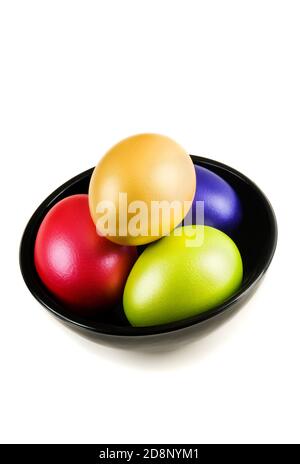 Groupe d'œufs de Pâques colorés dans la soucoupe sur fond blanc. Un bouquet d'œufs de pâques de couleur perle dans une soucoupe noire isolée sur blanc avec ombre. Studio Banque D'Images