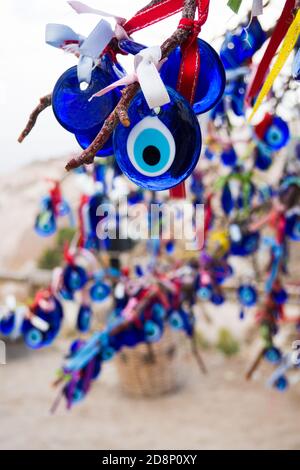L'amulette turque Nazar oeil bleu est fait de verre bleu. Il est suspendu sur un arbre décoré de rubans colorés. Banque D'Images