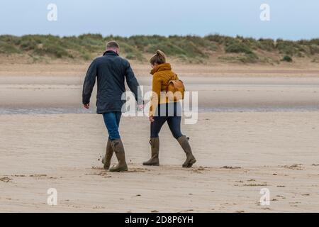 jeunes couples marchant sur la plage ensemble à la plage de sable de holkham hall sur la côte de norfolk. Banque D'Images