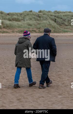 un couple plus âgé fait une promenade rapide sur la plage au bord de la mer à holkham, dans le nord de norfolk, au royaume-uni Banque D'Images