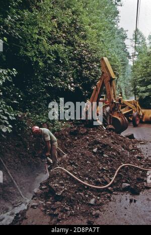 Un ouvrier de la construction traverse une roche solide le long de la rue Escowee, sur la rive de la rivière Chattahoochee, avant de poser un tuyau pour le premier système de traitement des eaux usées à Helen. Le projet est devenu une nécessité de prendre soin des touristes qui visitent la petite communauté de montagne de quelque 270 personnes. En 1969, des responsables locaux, des hommes d'affaires et des résidents ont approuvé la rénovation du quartier des affaires sur le thème des Alpes bavaroises. Son succès a attiré de nouvelles entreprises et de nouveaux touristes. Banque D'Images