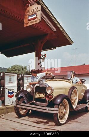 Warren Brown, propriétaire de la station-service et de l'épicerie sur main Street à Helen, en Géorgie, est assis dans une Ford 1929 tandis que son fils fait l'essence de la voiture; un des nombreux qu'il a ramassé au fil des ans Banque D'Images