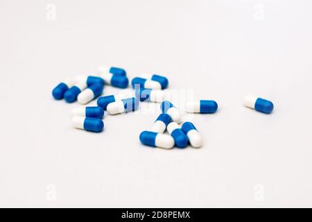 Photo gros plan des capsules médicales bleues regroupées au centre sur fond blanc. Le concept d'aider avec la douleur, l'empoisonnement, et la température élevée Banque D'Images