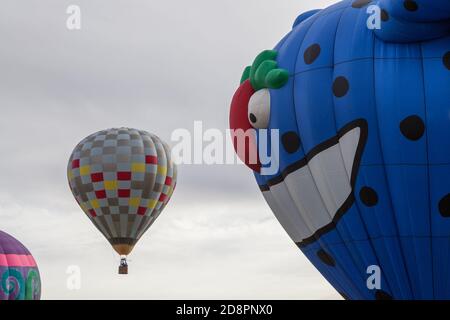 Un grand ballon monstre bleu regarde un ballon montant plus petit comme il veut le manger à la Balloon Fiesta au Nouveau-Mexique. Banque D'Images