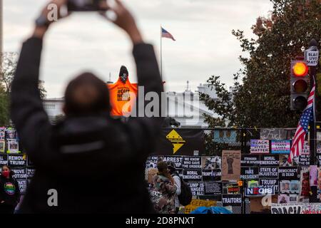 Washington, DC, Etats-Unis, 31 octobre 2020. Photo : visiteur de Black Lives Matter Plaza prenant une photo d'une figure sur un bâton au-dessus de la clôture de Lafayette Square à la Maison Blanche. La figure porte le sweat-shirt orange de refuser le fascisme, et porte le nom de leur initiative: Trump/Pence dehors maintenant! Il porte également un chapeau Black Lives Matter. La Maison-Blanche est visible derrière la figure. Photographié lors d'une marche organisée par refuser le fascisme DC pour protester contre les politiques fascistes et les abus de l'Administration Trump. Crédit : Allison C Bailey/Alay Live News Banque D'Images