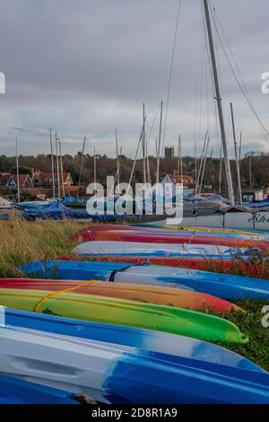 bateaux et canoës aux couleurs vives en ligne sur la rive, dans les puits situés à côté de la mer, sur la côte nord de norfolk, au royaume-uni Banque D'Images