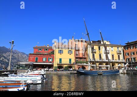 La vue sur les bateaux amarrés dans la station balnéaire de Malcesine aux cafés et restaurants. Malcesine est à la limite du lac de Garde dans le nord-est de l'Italie. Banque D'Images