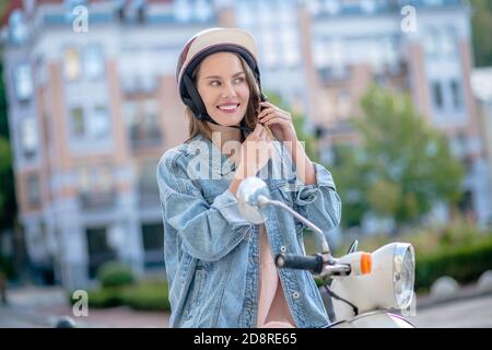 Femme portant un casque pendant que vous conduisez un scooter