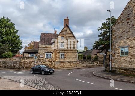 Scène de rue dans le joli village de Blisworth, Northamptonshire, Royaume-Uni; avec de vieilles maisons en pierre bordant la route. Banque D'Images