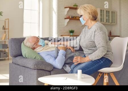 Femme âgée prenant soin de son mari malade couché canapé souffrant de la grippe ou du rhume Banque D'Images