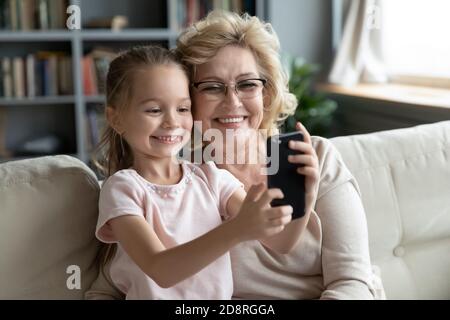 Petite fille mignon enregistrement drôle de vidéo mobile avec granny. Banque D'Images