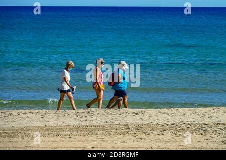 Personnes marchant sur les plages de sable, portant des masques faciaux, à la Mata, Torrevieja, Costa Blanca, Espagne, hiver, soleil d'hiver, destination Banque D'Images