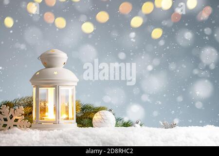 Lanterne blanche avec décorations de noël dans une neige sur le bleu arrière-plan Banque D'Images