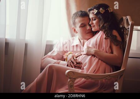 femme enceinte et homme en posant dans un intérieur classique par la fenêtre. en attendant un bébé. grossesse Banque D'Images