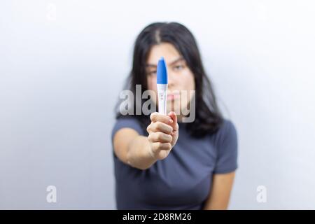 La jeune fille tient un test de grossesse positif dans sa main. Grossesse non planifiée. Mise au point sélective Banque D'Images