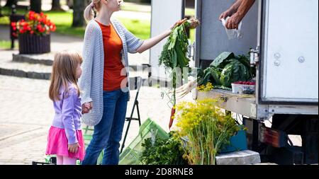 Mère et son enfant achètent des légumes frais, des produits alimentaires de l'épicerie mobile dans son camion. Parent et fille, famille shopping, marché agricole Banque D'Images