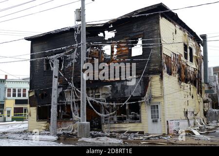 Un bâtiment brûlé dans un coin de rue en hiver. Le bâtiment est complètement brûlé et il semble qu'il va colaside. Banque D'Images