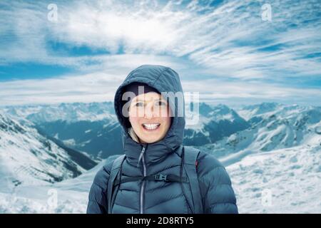 Une jeune femme à l'aspect naturel se tient devant une montagne portée et sourires à l'appareil photo Banque D'Images