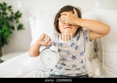 Portrait d'une fille de dépression qui dormait et qui tient la main sur l'alarme horloge Banque D'Images