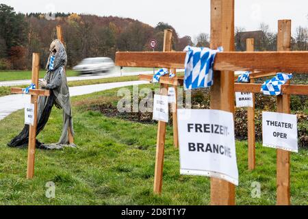 01 novembre 2020, Bavière, Greifenberg: Croix avec des signes sur lesquels les industries souffrant de restrictions de corona, telles que le commerce de détail, théâtre, opéra ou l'industrie des loisirs, sont nommés, et une représentation figurative de la mort, avec un manteau d'armes bavarois en forme de losange comme un porte-parole, sont placés le long d'une rue. L'installation est une action de protestation contre le verrouillage partiel de Corona. Les gouvernements fédéral et des États ont décidé d'un verrouillage partiel à partir de lundi prochain. Photo: Matthias balk/dpa Banque D'Images