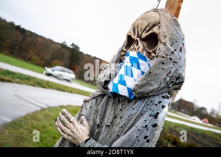 01 novembre 2020, Bavière, Greifenberg: Une représentation figurative de la mort avec un manteau de diamant bavarois comme masque facial peut être vu dans un cimetière symbolique sur une rue. L'installation est une action de protestation contre le verrouillage partiel de Corona. Les gouvernements fédéral et des États ont décidé d'un verrouillage partiel à partir de lundi prochain. Photo: Matthias balk/dpa Banque D'Images