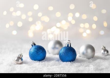 Décorations de Noël argentées et bleues sur la neige avec lumières de Noël floues. Banque D'Images