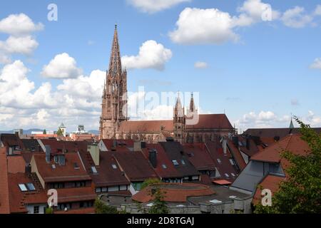 Freiburg Minster, cathédrale avec une grande tour parmi les toits de la vieille ville historique avec ciel bleu et quelques nuages sur le fond. Banque D'Images