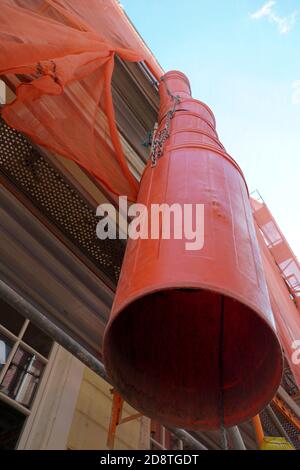 Goulotte de déchets ou goulotte de débris de couleur rouge sur une façade d'un bâtiment historique en reconstruction pour l'enlèvement des ordures. Vue en petit angle avec détails. Banque D'Images