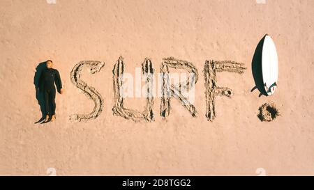 J'adore surfer. Vue de dessus d'un homme surfeur en combinaison avec une planche de surf sur le sable de la plage. S'amuser à l'école de surf. Banque D'Images