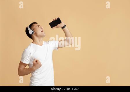 Un jeune homme heureux aime chanter avec un casque et utilise un smartphone Banque D'Images