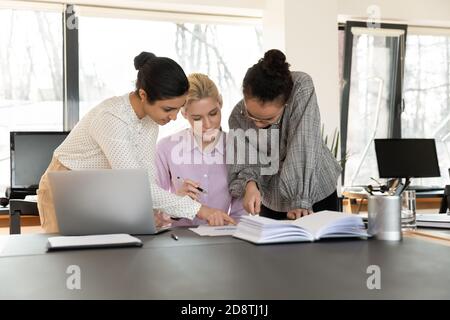 Jeunes concentrés divers collègues multiraciaux femmes analysant le rapport papier. Banque D'Images