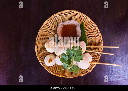 Boulettes de viande grillées sur un plat en panier de bois et une tasse de sauce décorée de coriandre placée sur la table en bois sombre. Vue de dessus Banque D'Images
